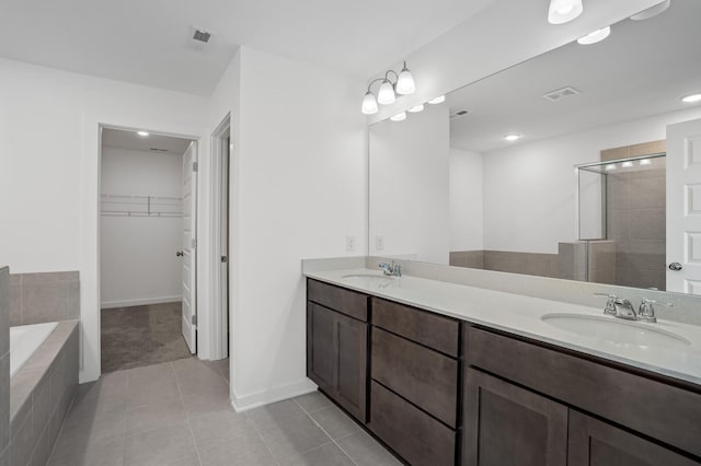 bathroom with tile patterned floors, visible vents, a sink, and a spacious closet