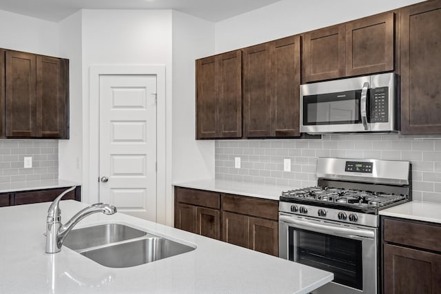 kitchen featuring light countertops, stainless steel appliances, a sink, and dark brown cabinets