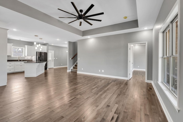 149 Watson Ct, Leoma, TN 38468 - unfurnished living room with wood finished floors, baseboards, ceiling fan, stairway, and a raised ceiling