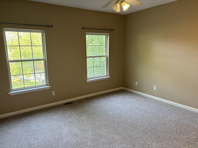 empty room with a ceiling fan, baseboards, visible vents, and carpet