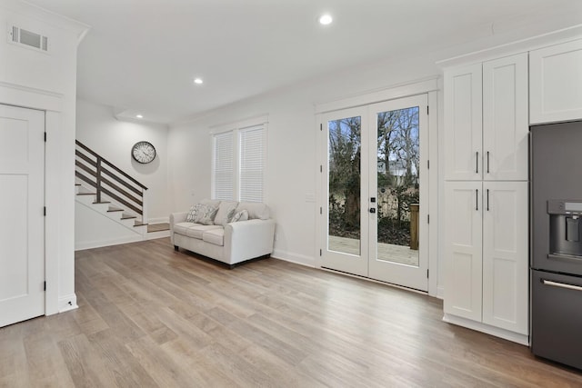 living area with french doors, light wood-style flooring, stairs, and visible vents