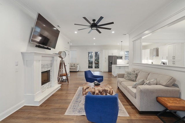 living room with a ceiling fan, a fireplace, wood finished floors, baseboards, and recessed lighting