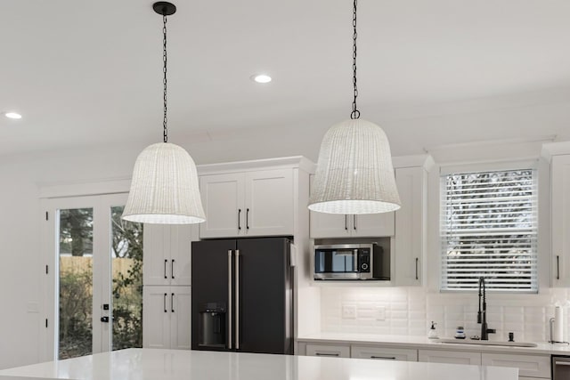 kitchen with a sink, light countertops, a chandelier, stainless steel appliances, and tasteful backsplash