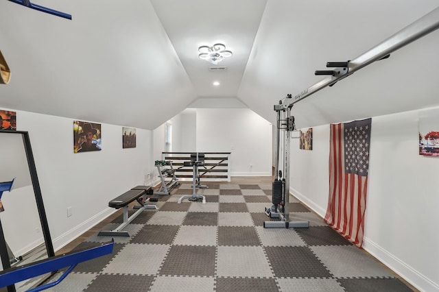 workout room featuring baseboards, vaulted ceiling, and visible vents