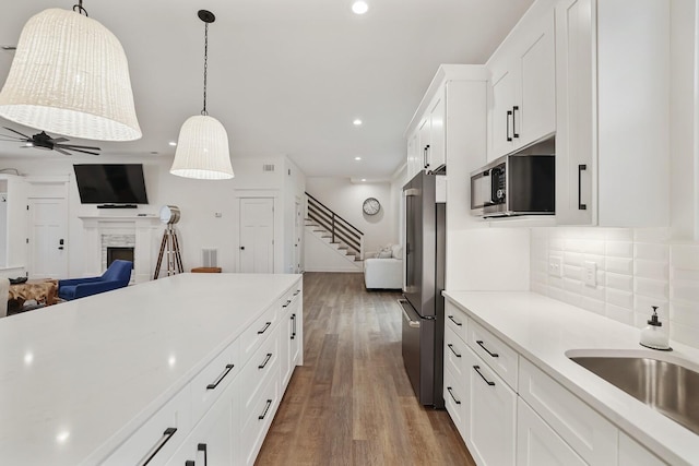 kitchen with light countertops, stainless steel appliances, open floor plan, and a ceiling fan