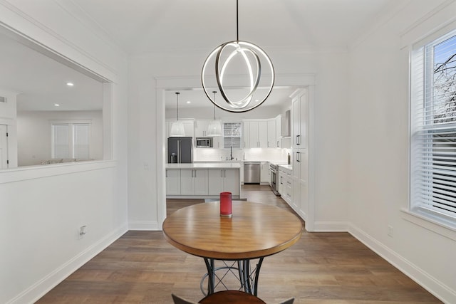 dining area with baseboards, ornamental molding, and wood finished floors