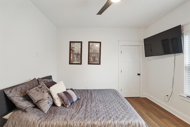 bedroom featuring baseboards, ceiling fan, wood finished floors, and multiple windows