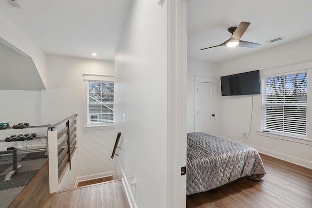 bedroom featuring visible vents, baseboards, wood finished floors, and multiple windows