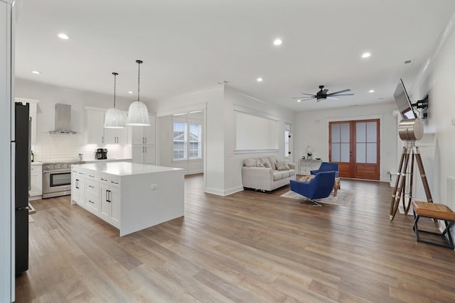 kitchen featuring light countertops, wall chimney exhaust hood, recessed lighting, and high end range