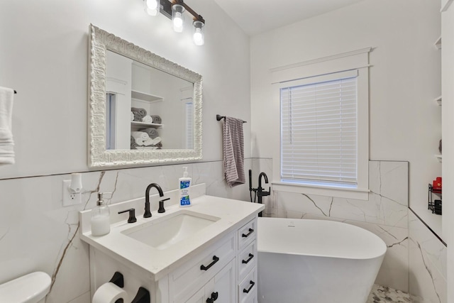 bathroom featuring vanity, tile walls, a wainscoted wall, and a freestanding bath