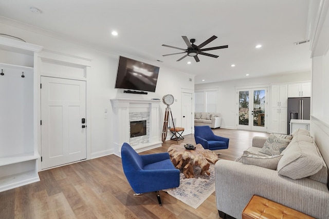 living room with a ceiling fan, a stone fireplace, visible vents, recessed lighting, and light wood-style flooring