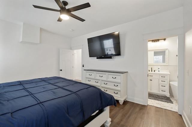bedroom with connected bathroom, a ceiling fan, baseboards, and dark wood-type flooring