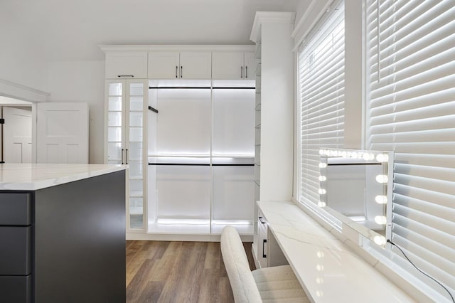 kitchen featuring light stone counters, white cabinets, and wood finished floors