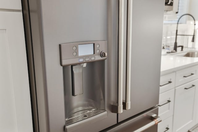 details featuring light countertops, white cabinetry, a sink, and stainless steel refrigerator with ice dispenser