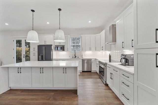 kitchen featuring white cabinets, appliances with stainless steel finishes, wall chimney exhaust hood, dark wood-type flooring, and a kitchen island