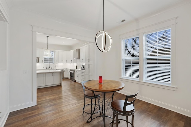 dining area featuring baseboards, ornamental molding, wood finished floors, and visible vents
