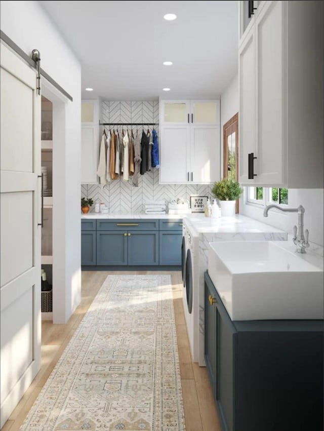 laundry room with recessed lighting, a barn door, light wood-type flooring, and washing machine and clothes dryer