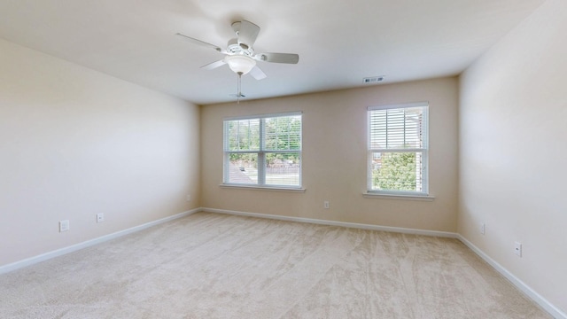 unfurnished room featuring baseboards, light carpet, a ceiling fan, and visible vents