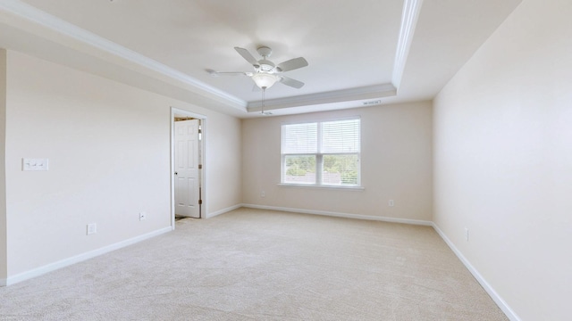 empty room featuring ceiling fan, visible vents, baseboards, light carpet, and a tray ceiling