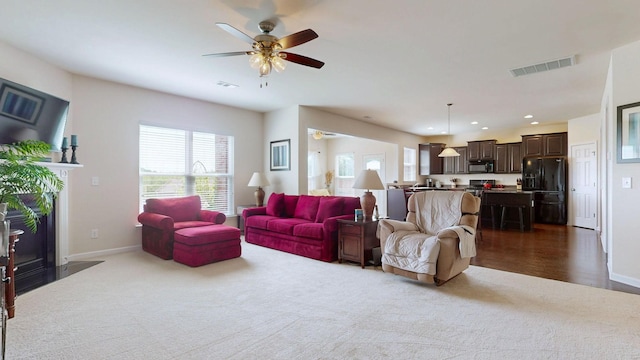 living area featuring carpet floors, a ceiling fan, baseboards, and visible vents