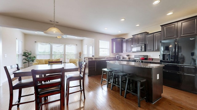kitchen featuring visible vents, black refrigerator with ice dispenser, a kitchen island, a healthy amount of sunlight, and stainless steel range oven