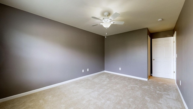 empty room with ceiling fan, light carpet, and baseboards