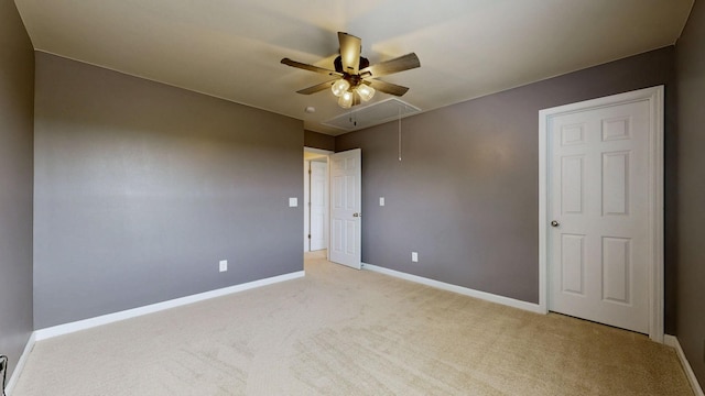unfurnished room with light colored carpet, attic access, baseboards, and a ceiling fan