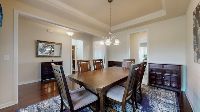 dining space with an inviting chandelier, crown molding, a tray ceiling, and wood finished floors