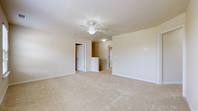 spare room featuring baseboards, ceiling fan, light carpet, and visible vents