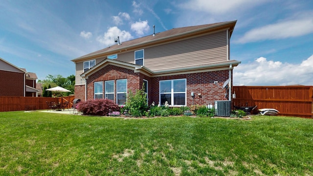 rear view of house with fence, a patio, a lawn, and brick siding