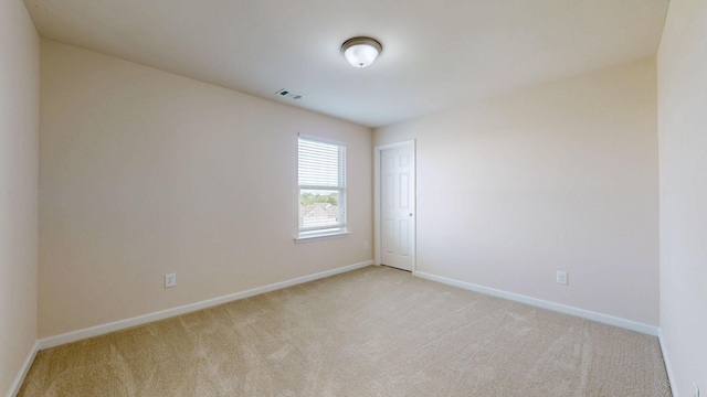 empty room featuring baseboards, visible vents, and light colored carpet
