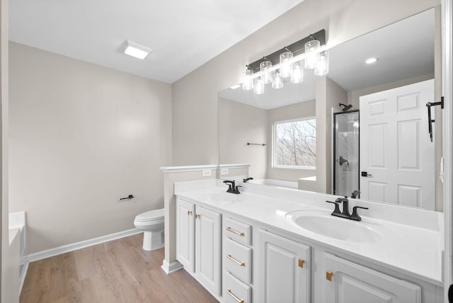 bathroom featuring a sink, a shower with shower door, wood finished floors, and toilet