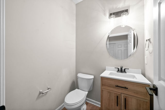 half bathroom featuring vanity, baseboards, wood finished floors, and toilet
