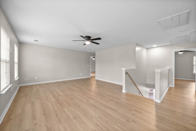 empty room featuring ceiling fan, visible vents, attic access, and light wood-type flooring