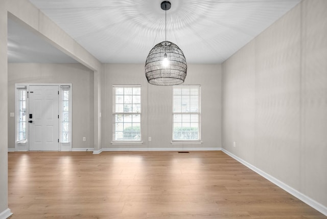 unfurnished dining area featuring baseboards and light wood finished floors