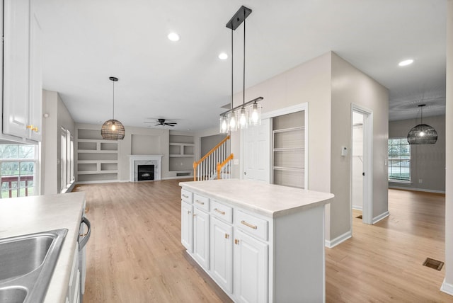 kitchen featuring a ceiling fan, light wood-style flooring, a fireplace, and built in shelves