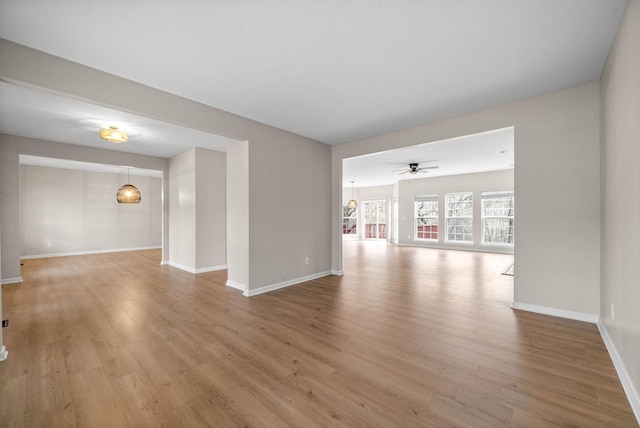 unfurnished living room with light wood-style floors, a ceiling fan, and baseboards