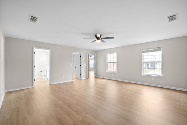 empty room featuring visible vents, a ceiling fan, light wood-style flooring, and baseboards