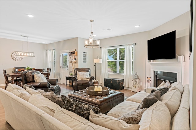 living area with recessed lighting, a notable chandelier, visible vents, and wood finished floors