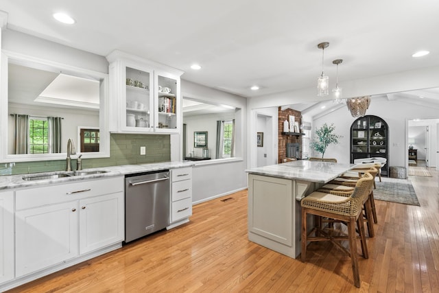 kitchen featuring decorative backsplash, dishwasher, a sink, open floor plan, and light wood-style floors