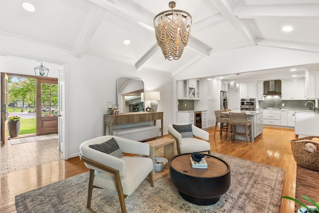 living area featuring light wood-style floors, lofted ceiling with beams, a chandelier, and recessed lighting