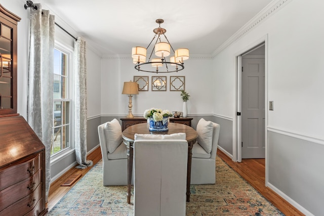 dining room with a healthy amount of sunlight, baseboards, wood finished floors, and a notable chandelier
