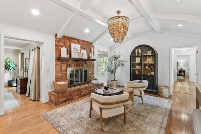 living area featuring an inviting chandelier, a brick fireplace, recessed lighting, hardwood / wood-style flooring, and lofted ceiling with beams