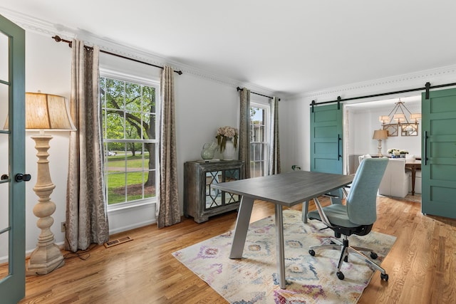 office area with light wood-style floors, crown molding, and a barn door