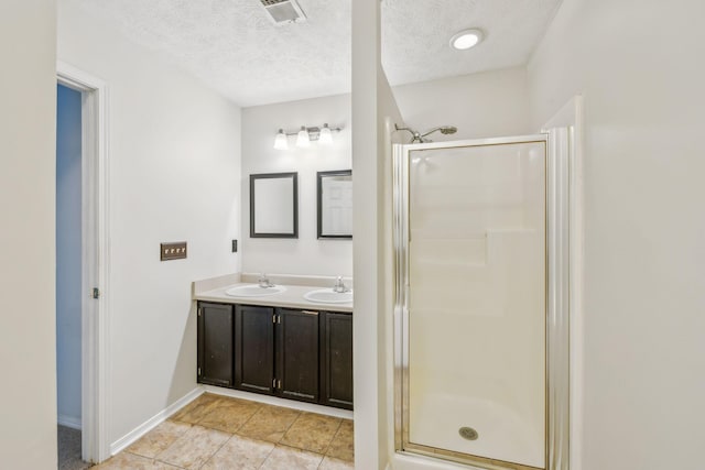 bathroom with visible vents, a sink, a textured ceiling, and a shower stall