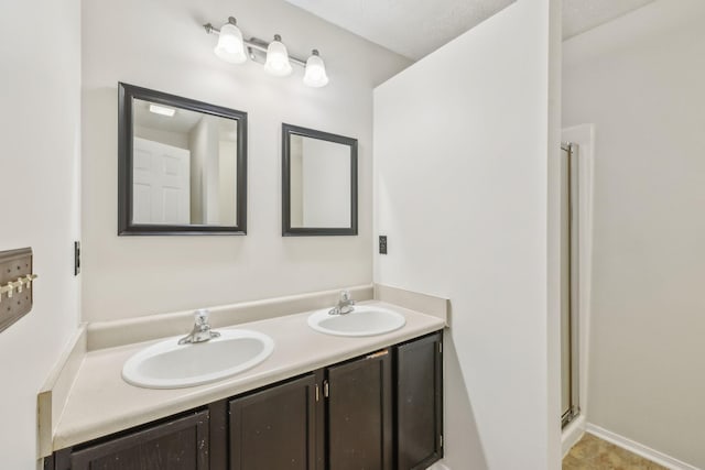 bathroom featuring double vanity, a sink, and a stall shower