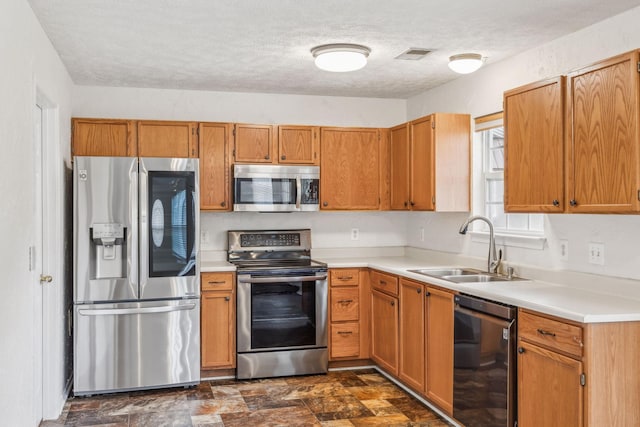 kitchen with visible vents, light countertops, a textured ceiling, a sink, and appliances with stainless steel finishes