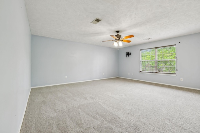 carpeted spare room with baseboards, ceiling fan, a textured ceiling, and visible vents