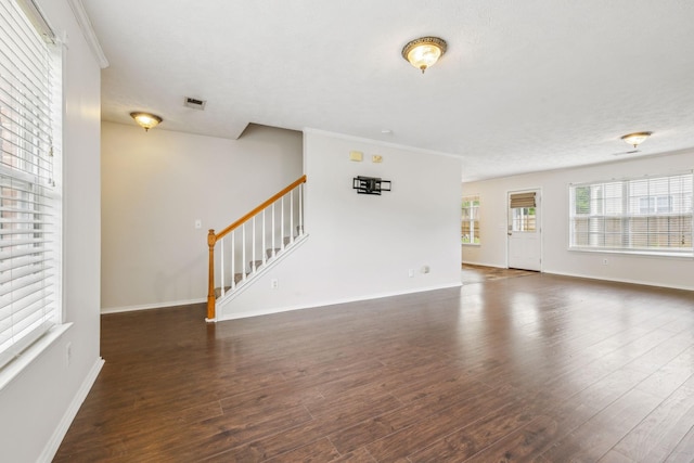 unfurnished living room with crown molding, visible vents, stairs, wood finished floors, and baseboards