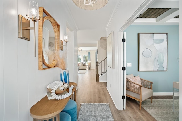hallway featuring baseboards, ornamental molding, light wood finished floors, and stairs